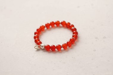 Carnelian bileziği. Doğal Carnelian taşlarından yapılmış bilezik. Doğal taşlardan yapılmış bilezik. El yapımı mücevherler. Hafif modern arka planda el yapımı bilezikler. Kalp.
