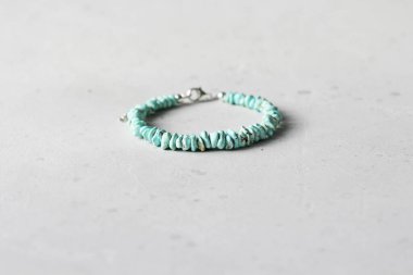 Turkuaz bilezik. Doğal Turkuaz taşından yapılma bilezik. Doğal taşlardan yapılmış bilezik. El yapımı mücevherler. Hafif modern arkaplanda el yapımı bilezikler.