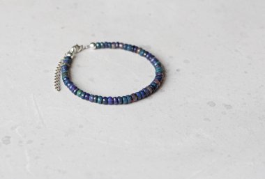 Siyah ateş opal bileziği. Eldeki taşlardan yapılmış bilezik. Siyah Ateş Opal 'den. Doğal taşlardan yapılmış bilezik. El yapımı mücevherler. Hafif modern arkaplanda el yapımı bilezikler.