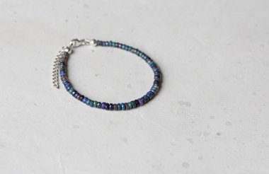 Siyah ateş opal bileziği. Eldeki taşlardan yapılmış bilezik. Siyah Ateş Opal 'den. Doğal taşlardan yapılmış bilezik. El yapımı mücevherler. Hafif modern arkaplanda el yapımı bilezikler.