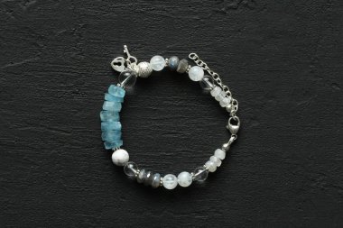 Doğal taşlar ve gümüşten yapılmış güzel bir asimetrik tasarım bileziği. Aquamarine, kaya kristali, kacholong, larimar, ay taşı. Siyah arka planda doğal taşlardan yapılmış el yapımı mücevherler..