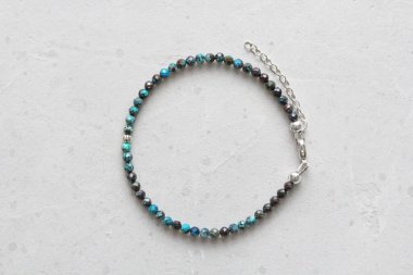 Chrysocolla bileziği. Elindeki bileklik doğal taştan yapılmış Chrysocolla. Doğal taşlardan yapılmış bilezik. Yazarın el yapımı mücevherleri. Hafif modern arkaplanda el yapımı bilezikler.