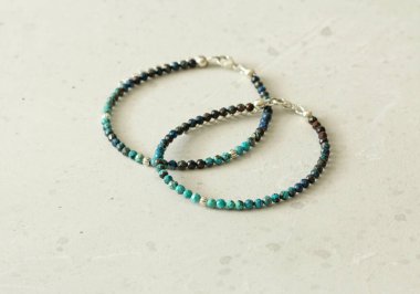 Chrysocolla iki bilezik. Elindeki bileklik doğal taştan yapılmış Chrysocolla. Doğal taşlardan yapılmış bilezik. Yazarın el yapımı mücevherleri. Hafif modern arkaplanda el yapımı bilezikler.