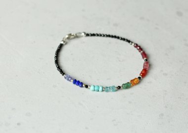 Parlak renkli bilezik. Yakut, mercan, carnelian, sitrin, zümrüt, apatit, amazonit, turkuaz, lapis lazuli, tanzanit, siyah spinel. Hafif modern arka planda el yapımı mücevherler..