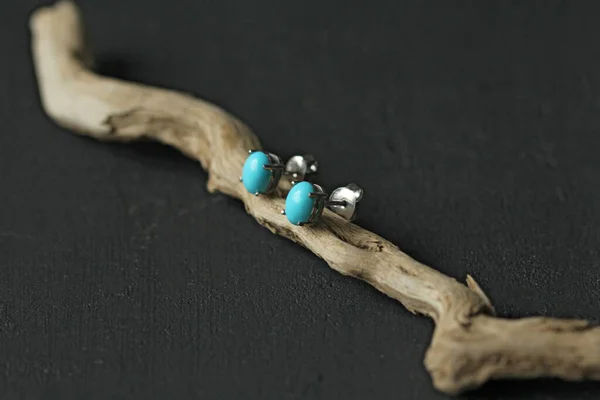 Stud earrings made of natural turquoise sleeping beauty. Designer earrings from natural turquoise stones. Women\'s jewelry on a black background and wood. Author\'s modern jewelry.