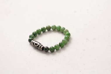 Nefrit taşı, Dzi boncuğu, bir göz bileziği. Doğal Nefrit kaynaklı taşlardan yapılmış bileklik. Hafif arka planda el yapımı mücevherler. Tibet boncukları 1. Budizm, arzuların yerine getirilmesi.