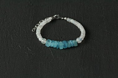 Aquamarine ve ay taşından el yapımı mücevherler, modern siyah arka planda. Doğal taşlar ve gümüşten yapılmış güzel bir bilezik. Aquamarine, ay taşı.