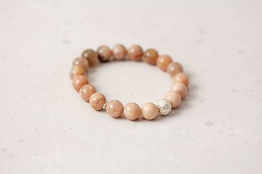 Güneş taşı bileziği. Bilezik, eldeki taşlardan yapılmış. Güneş taşı. Doğal taşlardan yapılmış bilezik. El yapımı mücevherler. Hafif modern arkaplanda el yapımı bilezikler.