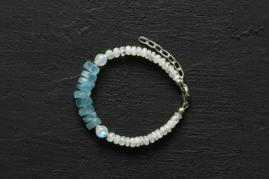Aquamarine ve ay taşından el yapımı mücevherler, modern siyah arka planda. Doğal taşlar ve gümüşten yapılmış güzel bir bilezik. Aquamarine, ay taşı.