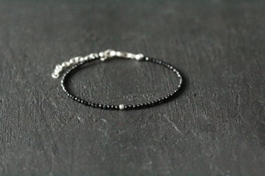 Siyah spinel, turmalin gümüş ince bilezik. Eldeki taşlardan yapılmış bilezik. Siyah, doğal taştan. Doğal taşlardan yapılmış el yapımı bileklik. Siyah modern arkaplanda el yapımı bilezikler.