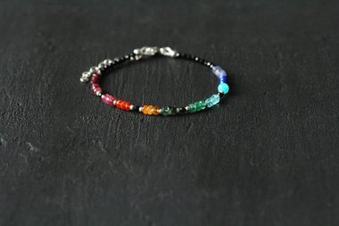 Doğal taştan yapılmış, parlak renkli, ince el yapımı bir bilezik. El yapımı mücevherler. Yakut, turmalin, carnelian, zümrüt, apatit, amazonit, lapis lazuli, tanzanit, siyah spinel ve gümüş..