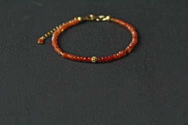 Doğal Carnelian ince bileziği. Doğal Carnelian taşlarından yapılmış bilezik. Doğal taşlardan yapılmış bilezik. El yapımı mücevherler. Siyah modern arka planda el yapımı bilezikler. Altın kaplama..