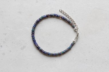 Siyah ateş opal bileziği. Eldeki taşlardan yapılmış bilezik. Siyah Ateş Opal 'den. Doğal taşlardan yapılmış bilezik. El yapımı mücevherler. Hafif modern arkaplanda el yapımı bilezikler.