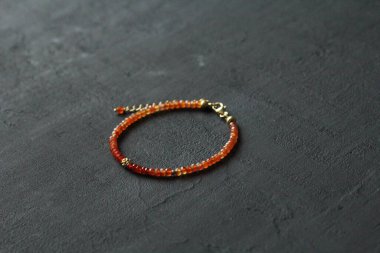 Doğal Carnelian ince bileziği. Doğal Carnelian taşlarından yapılmış bilezik. Doğal taşlardan yapılmış bilezik. El yapımı mücevherler. Siyah modern arka planda el yapımı bilezikler. Altın kaplama..