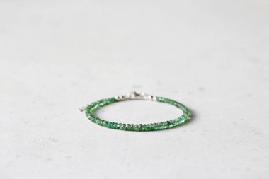 Zümrüt ince, güzel bilezik. Doğal taştan yapılmış zümrüt bilezik. Doğal taşlardan yapılmış bilezik. El yapımı mücevherler. Hafif modern arkaplanda el yapımı bilezikler.
