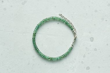 Zümrüt ince, güzel bilezik. Doğal taştan yapılmış zümrüt bilezik. Doğal taşlardan yapılmış bilezik. El yapımı mücevherler. Hafif modern arkaplanda el yapımı bilezikler.