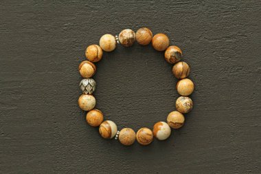 Jasper bej bilezik ve gümüş boncuklu. Doğal taşlardan yapılmış bilezik, Jasper. El yapımı mücevherler. Siyah modern arkaplanda el yapımı bilezikler.