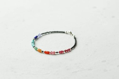 Parlak renkli bilezik. Yakut, mercan, carnelian, sitrin, zümrüt, apatit, amazonit, turkuaz, lapis lazuli, tanzanit, siyah spinel. Hafif modern arka planda el yapımı mücevherler..