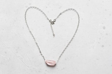 Doğal taştan kolye, gül kuvars gümüş zinciri. Yazar mücevherleri, Rose Quartz minerallerinden. Tasarımcı mücevherleri. Hafif modern arka planda. Zincirli taş, boyunluk.