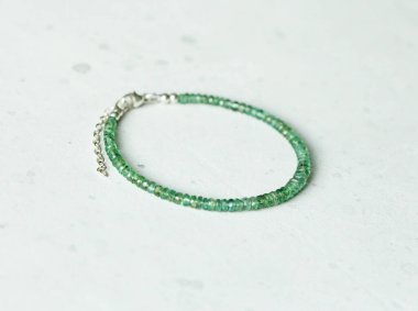 Zümrüt ince, güzel bilezik. Doğal taştan yapılmış zümrüt bilezik. Doğal taşlardan yapılmış bilezik. El yapımı mücevherler. Hafif modern arkaplanda el yapımı bilezikler.