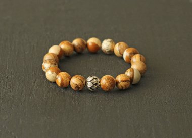 Jasper bej bilezik ve gümüş boncuklu. Doğal taşlardan yapılmış bilezik, Jasper. El yapımı mücevherler. Siyah modern arkaplanda el yapımı bilezikler.