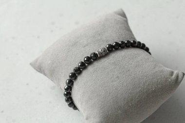 Siyah spinel, turmalin bilezik. Eldeki taşlardan yapılmış bilezik. Siyah dönme dolap, turmalin. Doğal taşlardan yapılmış bilezik. Hafif modern arka planda el yapımı mücevherler..
