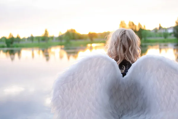woman with white angel wings. wearing black leather clothes. fallen dark angel. demon. beast. girl in angel costume on halloween.