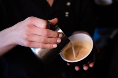 Kahveci tarafından yapılan latte sanatı. Kahveye süt dökmek. koyu kahve evi.