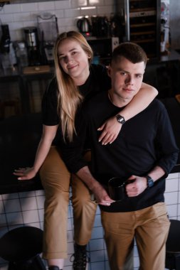 Tıpatıp aynı kıyafetleri giyen mutlu evli bir çift modern kahve dükkanında kafe sahipleri ya da işçiler gibi görünüyor. Aile işi. Çatı katı kafe.