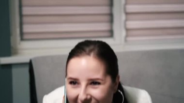 Gri ofiste telefonla konuşan mutlu, şaşırmış, esmer iş kadınının portresi. İyi ki aradın. Başarı, zafer, hediye. yavaş çekim