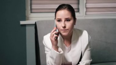 Üzgün, kızgın ve üzgün esmer iş kadını gri ofiste telefonla konuşuyor. Rahatsız edici, kötü bir telefon görüşmesi. Sorunlar, sorunlar. yavaş çekim