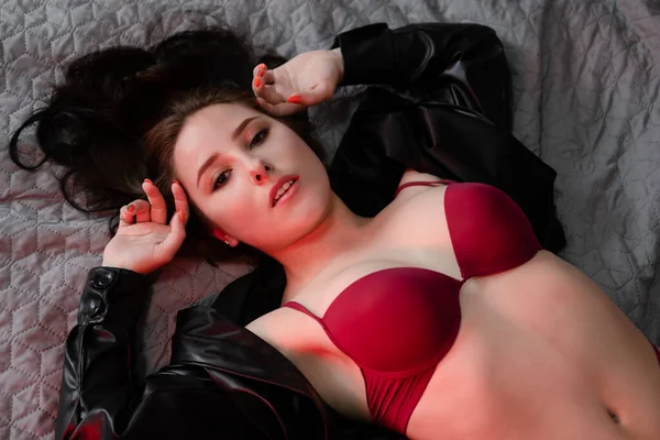 Sexy Zelfverzekerde Brunette Vrouw Rood Ondergoed Lederen Jas Grijs Bed — Stockfoto