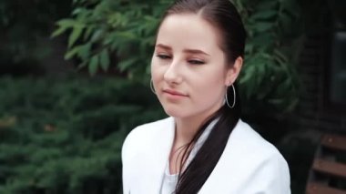 Açık havada poz veren kırmızı ve beyaz elbiseli çekici esmer kadın. Yaz mevsimi, yeşil ağaçlar. yavaş çekim