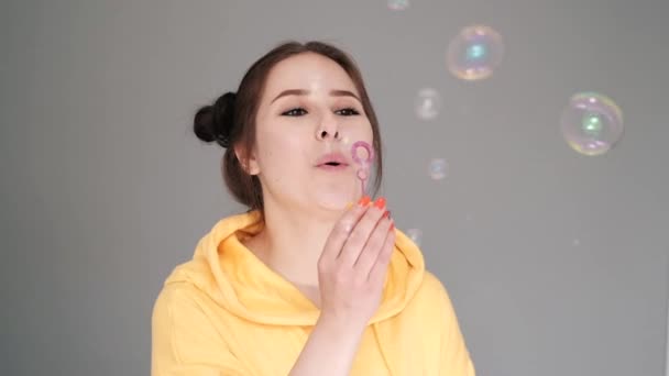 Happy Brunette Woman Yellow Hoodie Soap Bubbles Bright Grey Room — Stock Video