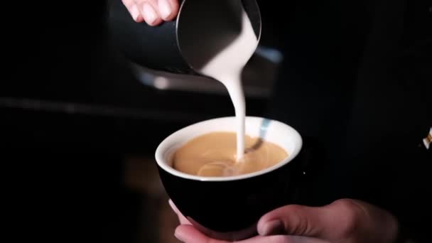 Barista giet latte foam op koffie, espresso. het creëren van een perfecte latte kunst. donkere kleuren, koffiehuis. slow motion — Stockvideo