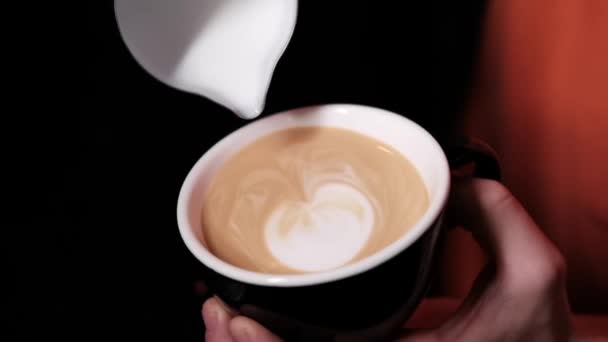 Barista giet latte foam op koffie, espresso. het creëren van een perfecte latte kunst. donkere kleuren, koffiehuis. slow motion — Stockvideo