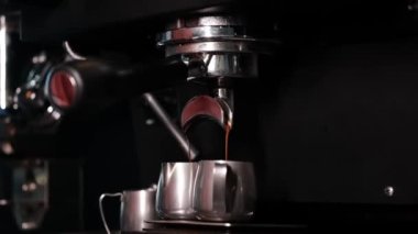 Profesyonel kahve makinesinden sade kahve dökülüyor. Kahve yapan barista. Koyu kahve dükkanı. yavaş çekim