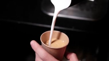 Kahveci tarafından yapılan latte sanatı. Kahveye süt dökmek. Koyu kahve evi. yavaş çekim