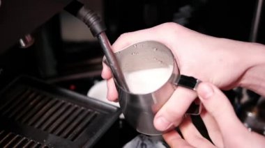 Süt köpüğünü kapuçino ya da latte, ısıtma ve kırbaçlama için hazırlama süreci. Barista sütü sürahide buharlaştırıyor. yavaş çekim