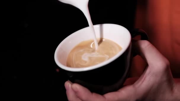 ラテアートbyバリスタ。コーヒーに牛乳を注ぐ。ダークコーヒーハウス。スローモーション — ストック動画