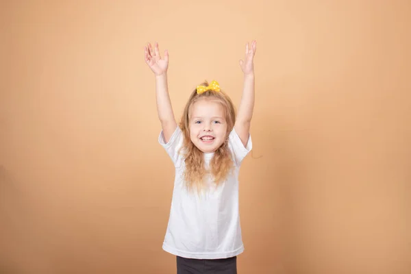 Adorável menina loira em t-shirt branca. em marrom - fundo amarelo. retrato criança inocência — Fotografia de Stock