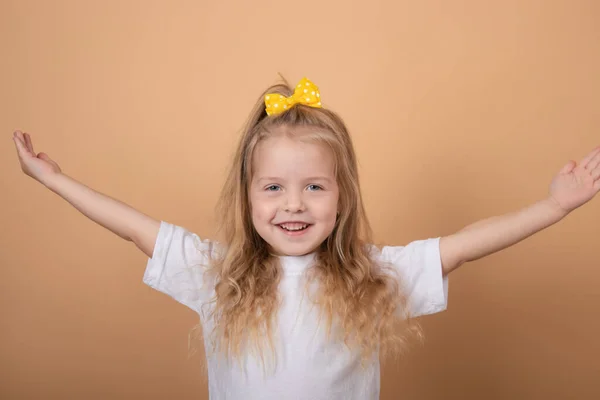 Adorable niña rubia en camiseta blanca. sobre marrón - fondo amarillo. retrato infantil inocencia —  Fotos de Stock