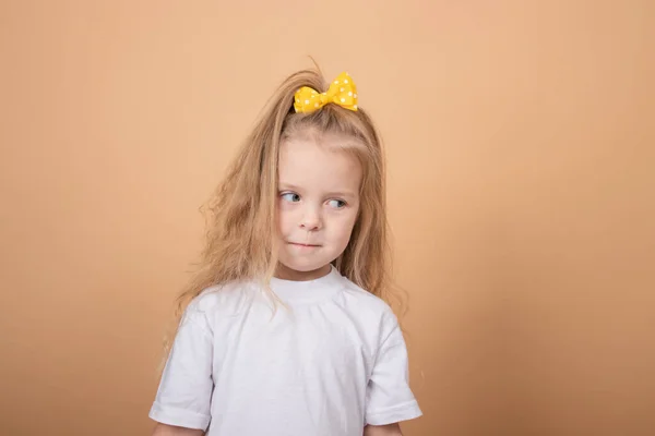 Rozkošná blondýnka v bílém tričku. na hnědém - žlutém pozadí. dětský portrét nevinnosti — Stock fotografie