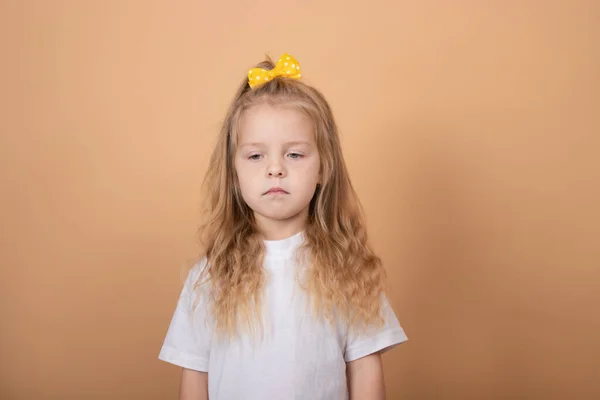 Adorável menina loira em t-shirt branca. em marrom - fundo amarelo. retrato criança inocência — Fotografia de Stock