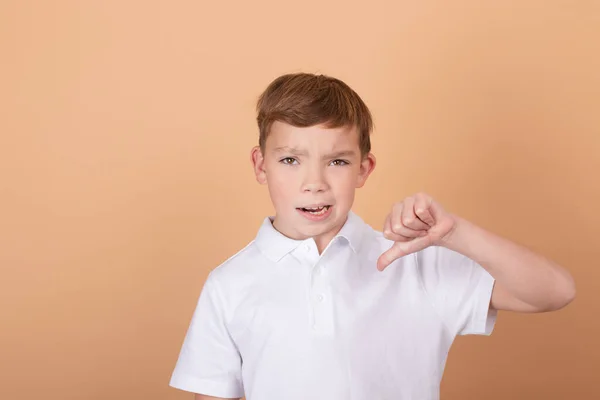 Gyönyörű tinédzser fiú elszigetelt barna háttér mutat ellenszenv - hüvelykujj lefelé gesztus - negatív kifejezés és rosszallás — Stock Fotó