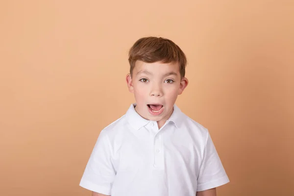 Emocionální portrét mladého chlapce teenagera. okouzlující školák. Krásné dítě. na světle hnědém pozadí — Stock fotografie