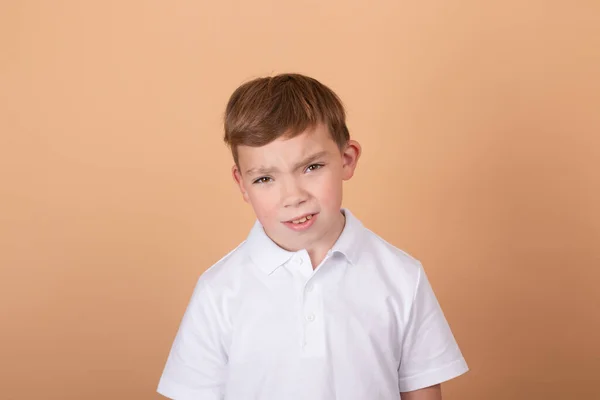 Emocionální portrét mladého chlapce teenagera. okouzlující školák. Krásné dítě. na světle hnědém pozadí — Stock fotografie