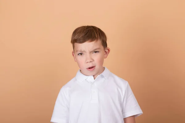 Retrato de menino de escola com expressão facial isolada sobre fundo marrom claro. Conceito de sentimentos, juventude, moda, expressão facial, emoções, estilo de vida, anúncio — Fotografia de Stock