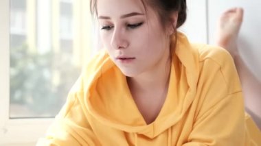 Sarı kapüşonlu güzel esmer kız. Parlak beyaz odada yapboz oyununun parçalarını düzenliyor. Masa oyunu evi oynanıyor.