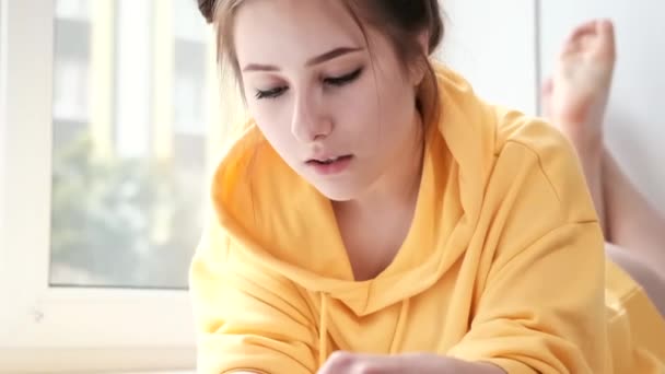 Pretty brunette girl in yellow hoodie arranging pieces of a Jigsaw Puzzle Game in bright white room. playing board game home. — Stock Video